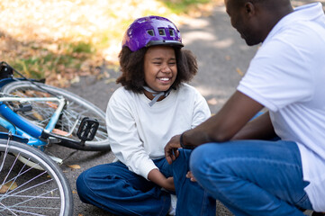 Dad helping his son after falling down from a bike