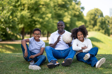 Fototapeta premium Cute happy african american family spending weekend in the park