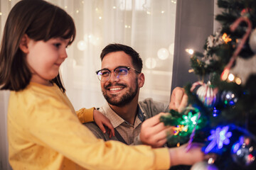 Loving father celebrates Christmas with his daughter by the beautiful Christmas tree