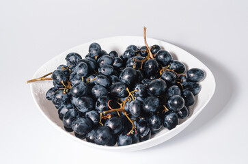 Blue grapes bunches on white plate. Healthy nutrition, health