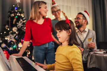 Family while enjoying music that their daughter playing on piano during Christmas time
