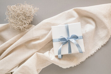 Wrapped gift box on beautifully laid out linen fabric. Holiday mockup.