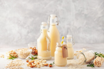 Dairy free alternative nut milk in glass bottles on a gray background. Healthy vegan food concept.