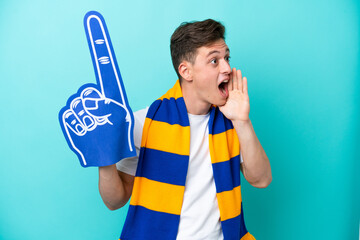 Young sports fan man isolated on blue background shouting with mouth wide open to the side