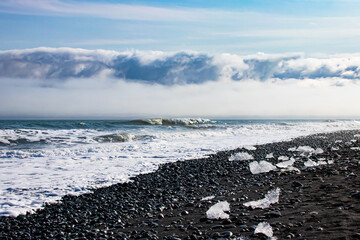 Ice floes on black volcanic sand on Diamond Beach in Iceland on a sunny day while travelling