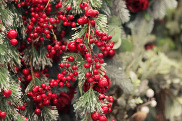 Artificial Christmas tree branches with clusters of red berries, artificial snow. New Year's decor. Close-up of Christmas tree decorations. Selling New Year's decor in a supermarket