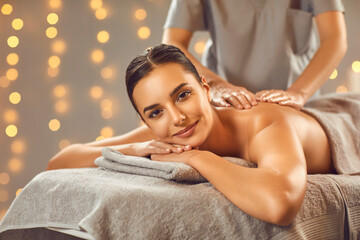 Relaxed young woman getting hot stone massage at wellness center. Beautiful serene girl lying on...