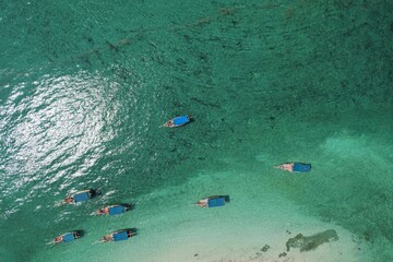 Aerial top view of several boats sailing in the tranquil ocean on a beautiful summer day