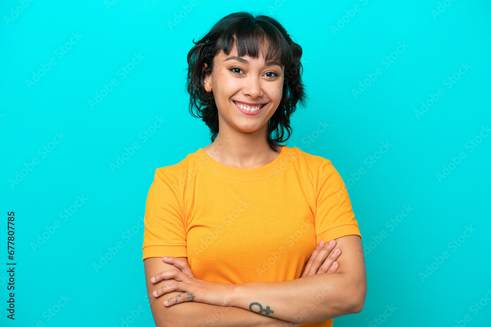 Wall mural Young Argentinian woman isolated on blue background keeping the arms crossed in frontal position