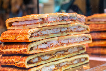 A stack of meat empanadas, in the shop window.