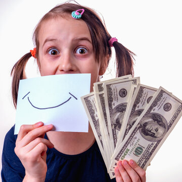 Conceptual image of beautiful young girl holding US Dollar money and banner with fake smile as symbol: money can't buy happiness.