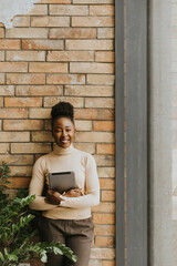 Fototapeta na wymiar One young African American business woman with digital tablet standing by the brick wall in the industrial style office
