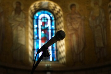 Closeup of a microphone in a church with a blurred background of a colorful window