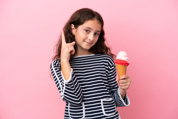 Little caucasian girl holding an ice cream isolated on pink background pointing up a great idea