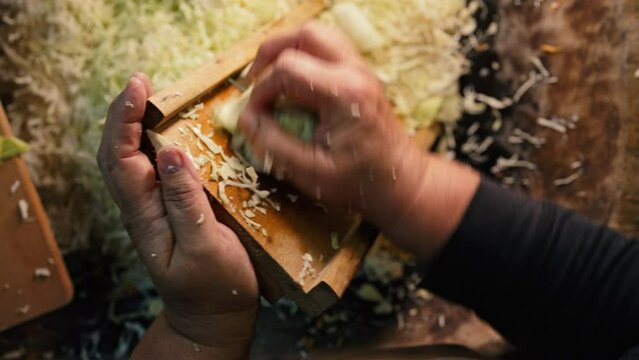 Woman rubs cabbage on grater, cooking traditional ukrainian fermented - sauerkraut salad from shredded carrot.