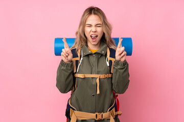Teenager Russian mountaineer girl with a big backpack isolated on pink background with fingers...