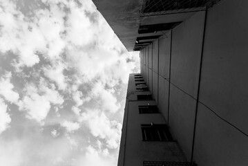 Low-angle grayscale shot of a residential building under a cloudy sky.