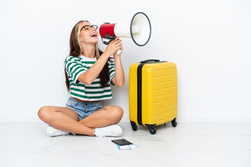 woman with suitcase sitting on the floor shouting through a megaphone