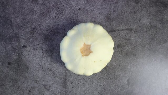 Patisson rotates against a dark background. View from above. Raw vegetable.