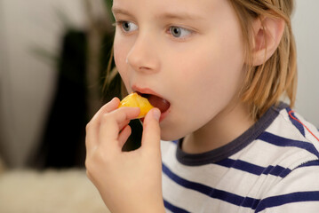 Nourishing bite: A young boy takes a nourishing bite of a juicy yellow plum, relishing the healthful fruit goodness