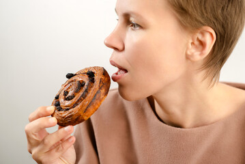 Flavorful enjoyment: A woman of allure delights in a raisin roll, relishing the flavorful enjoyment...