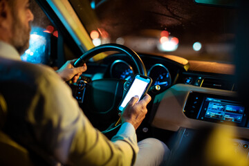 Back view man driving car checking smartphone at traffic stop