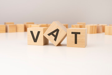 three wooden cubes with VAT symbols on them. white background. in the background there are many...