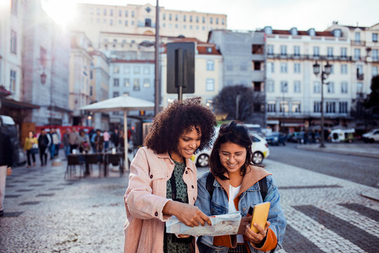 Diverse Female Friends Exploring City with Map and Smartphone