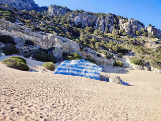 Tsambika beach with golden sand and a big Greek flag painted on a boulder. Rhodes Island, Greece.