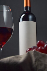 Graceful image capturing a red wine bottle alongside a glass and grapes, viewed from a low angle,...