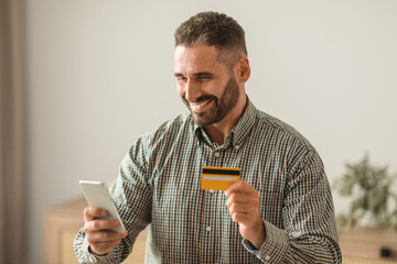 man making payments online with cellphone and credit card indoor