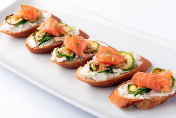 Vassoio di deliziosi crostini conditi con crema di formaggio, zucchine e salmone affumicato,...