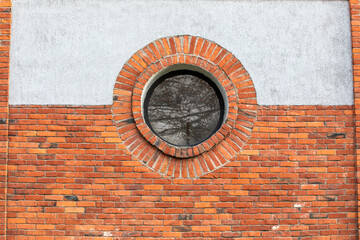 Round window. Red brick wall and light plaster