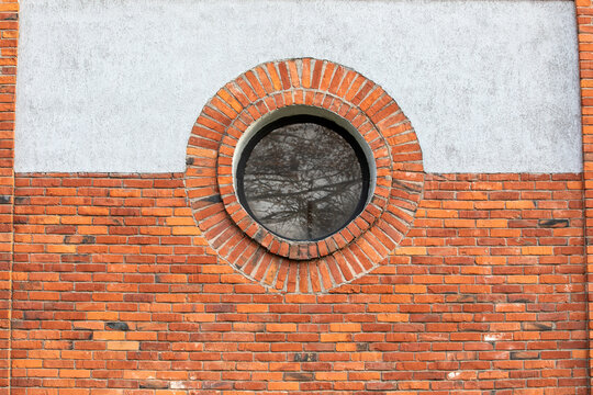 Fototapeta Round window. Red brick wall and light plaster