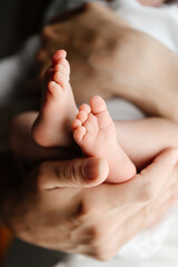 A mother holds the small legs of her newborn baby in her hands.