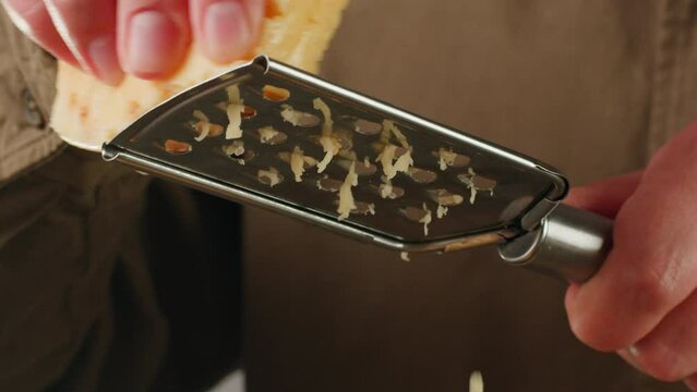 Italian cheese grater closeup, Close up of grated cheese, grating for pasta or pizza. Parmesan or gouda cooking by chef in cafe.