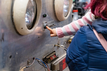A child's hand pressing a button in a workshop