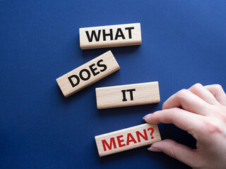 What does it mean symbol. Wooden blocks with words What does it mean. Beautiful deep blue background. Businessman hand. Business and What does it mean concept. Copy space.