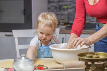 Adorable blond little child boy baking cake in domestic kitchen. Happy child having fun with working in the kitchen. Little helper