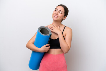 Young sport girl going to yoga classes while holding a mat isolated on white background looking up...