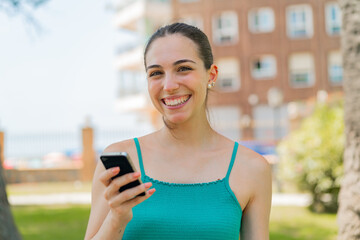 Young pretty woman using mobile phone at outdoors smiling a lot