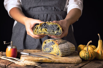 Homemade sourdough activated charcoal black bread with pumpkin turmeric oven baked and housewife woman baker with autumn seasonal food, old rustic style - obrazy, fototapety, plakaty