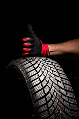 Car tire service and thumb hand of mechanic hold tyre black background copy space for text