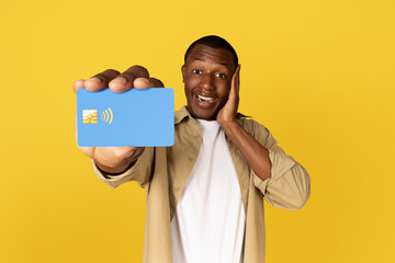 Happy millennial black guy in casual show credit card, enjoy shopping