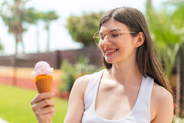 Young pretty Ukrainian woman with a cornet ice cream at outdoors with happy expression