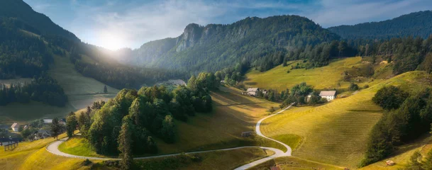 Foto op Plexiglas Country road green hills landscape with curved rural road blue sky with clouds Alpine mountains © kucherav
