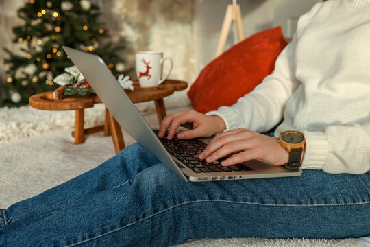 Close up of woman hands with, gifts, coffee cup and laptop. Online shopping at Christmas holidays. Freelance girl woking from home office. Female typing at notebook computer. Christmas moments