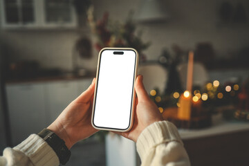 Phone in hands with isolated screen on Christmas kitchen background