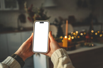 Phone in hands with isolated screen on Christmas kitchen background