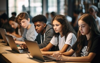 Teen students learning on laptop computers in ful modern classroom with wooden desks